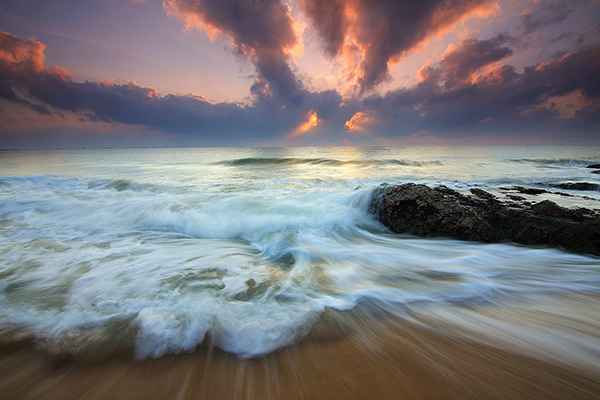 Sea waves crashing on to shore with soft motion blur against evening sky.
